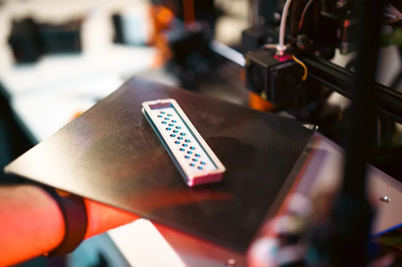 Funkční 3D tištěný konstrukční díl na podložce 3D tiskárny v dílně