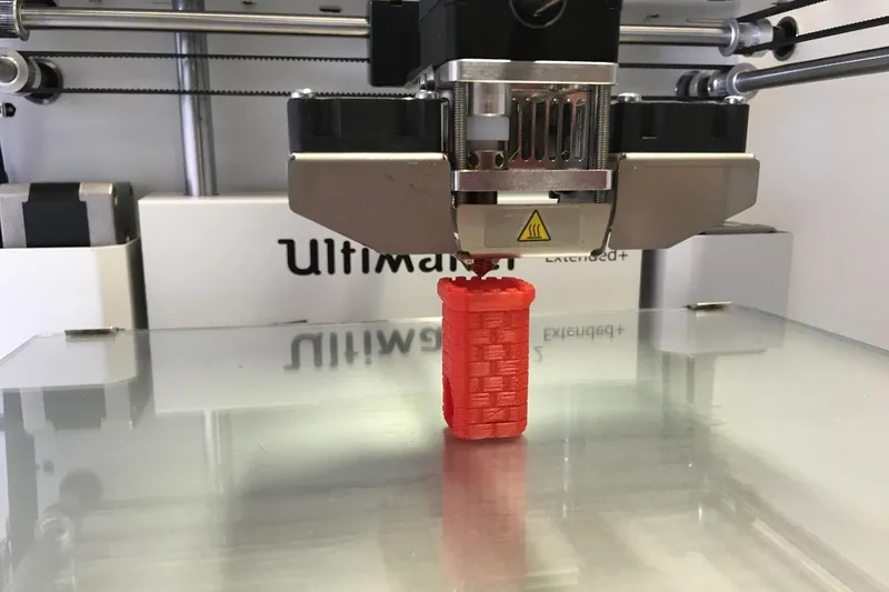 Detail trysky 3D tiskárny při tisku první vrstvy plastu na podložku