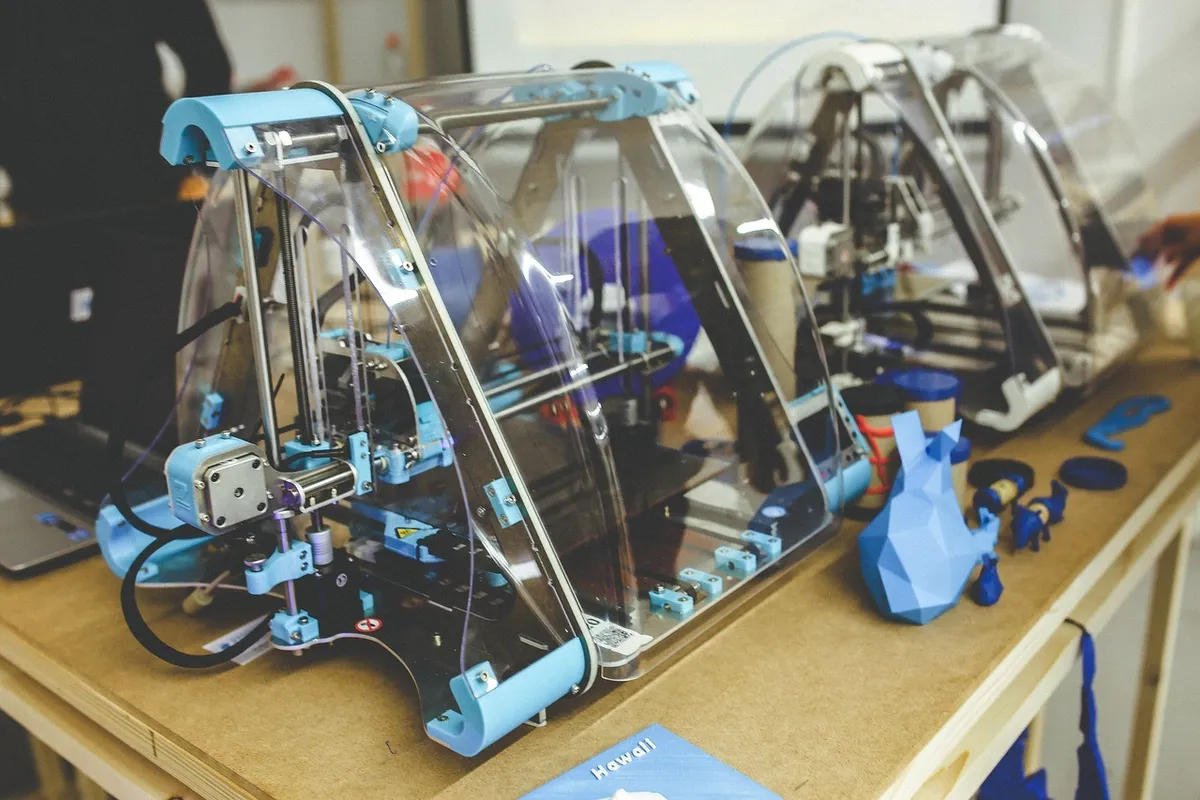 Stolní 3D tiskárny s vytištěnými modely na pracovním stole v dílně
